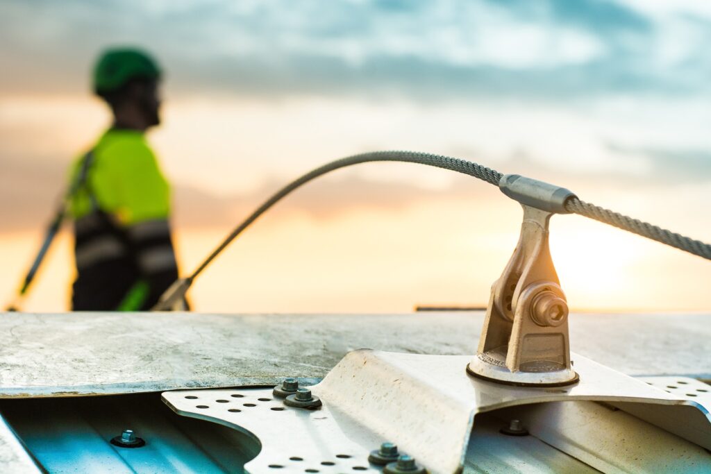 Worker attached to a fall arrest lifeline system on an industrial roof