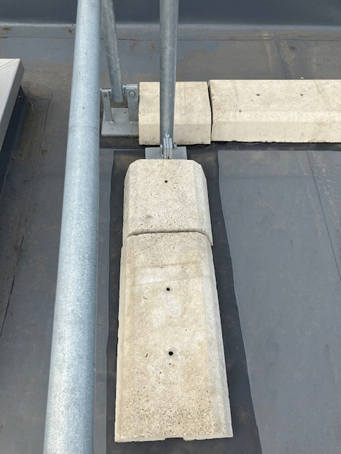 Concrete slabs used to as weights on a guardrail system