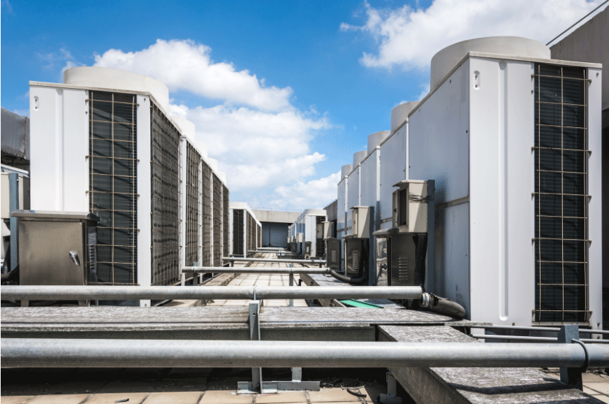 Congested rooftop with pipework and air conditioning units on it.