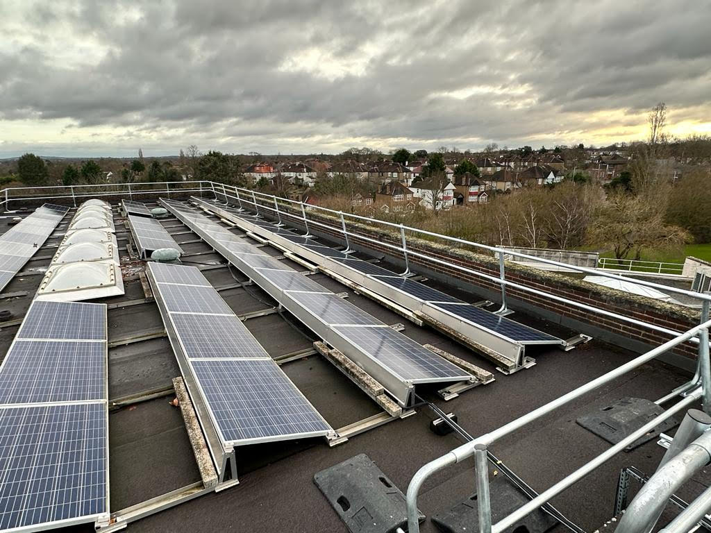 Solar panels on a roof with guardrails around the roof for collective protection. 