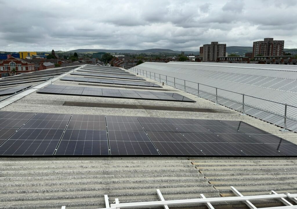 Solar panels on an industrial roof. A guardrail and lifeline enable safe maintenance of the panels.