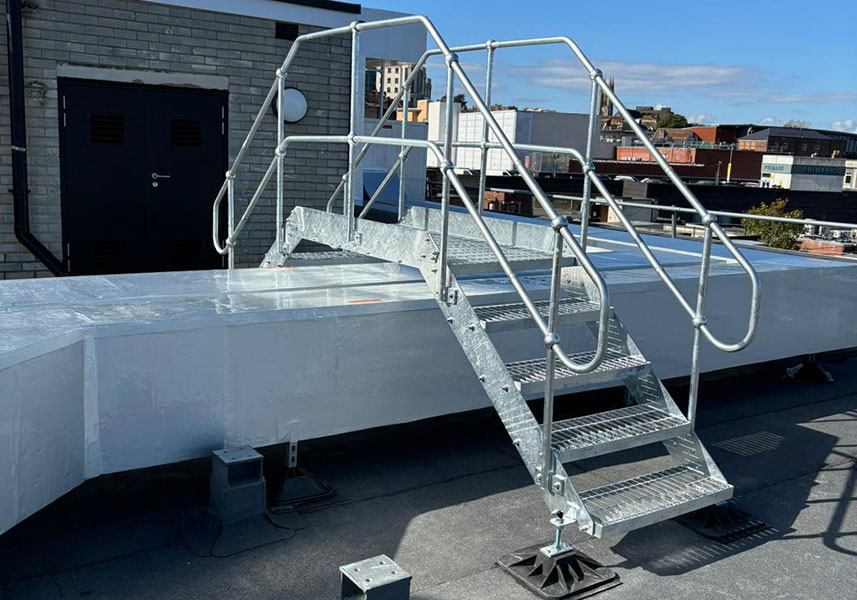 A step over platform spanning large pipework on a roof.