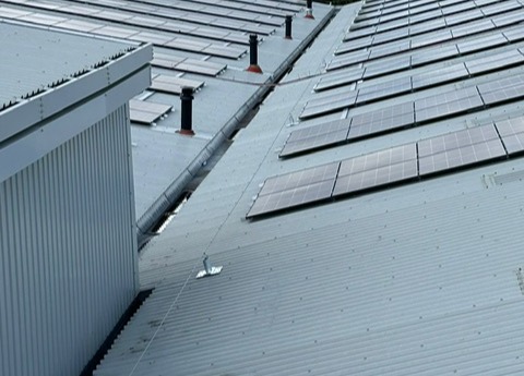 Horizontal lifelines on an industrial roof with solar panels on it