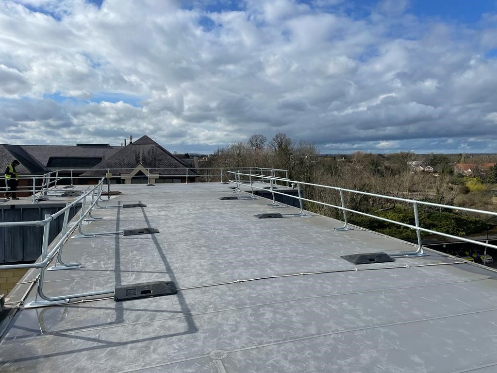 Flat commercial roof with freestanding fall protection guardrails installed along the edge, providing safe access for working at height.