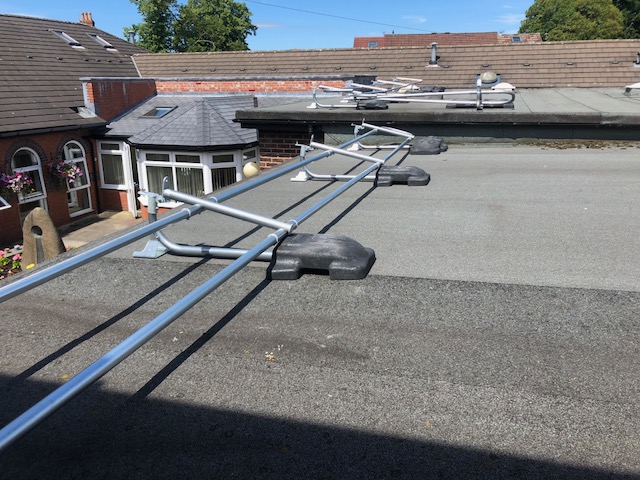 Flat roof with collapsible fall protection guardrail system, designed to provide edge safety while allowing temporary access and flexibility for maintenance work.